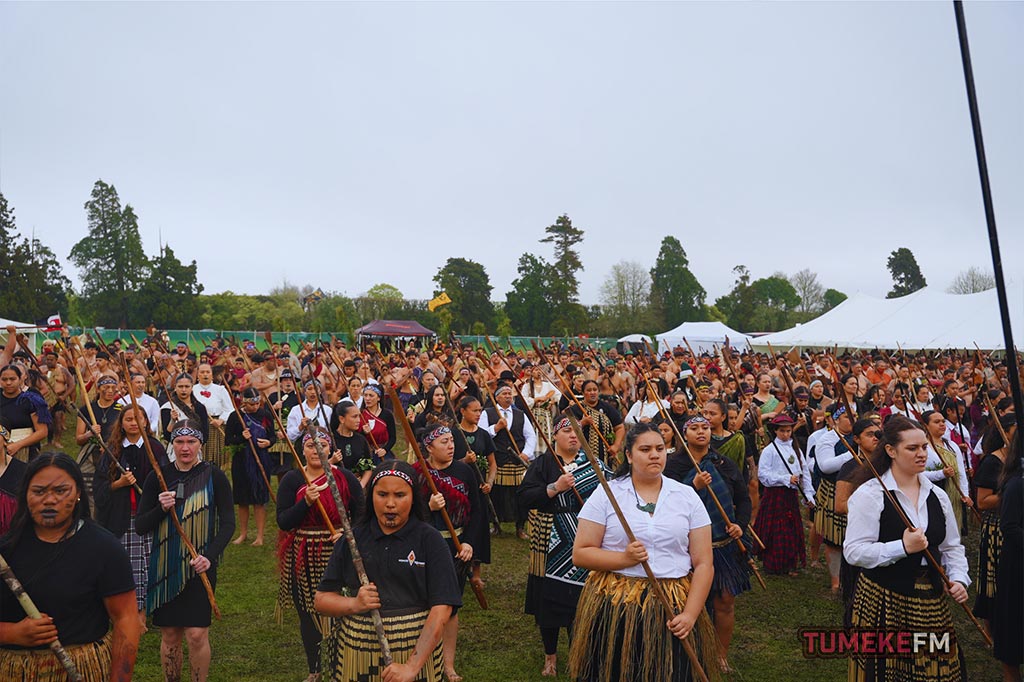 Large group of people with taiaha preforming at a Tumeke FM Kapa Haka event